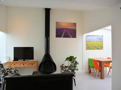 a living room with a fireplace and a table with chairs at Charming Garden Retreat in Noordwijkerhout
