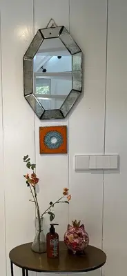 a mirror on a wall above a table with a vase at Sunny Guesthouse in Bergen