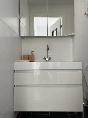 a white bathroom with a sink and a mirror at Blue Shell With Private Parking Garage in Zandvoort