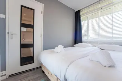 a bedroom with two white beds and a window at Blue Shell With Private Parking Garage in Zandvoort