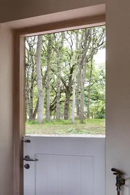 a door with a window looking out at trees at Bosvilla Kennemerduinen in IJmuiden