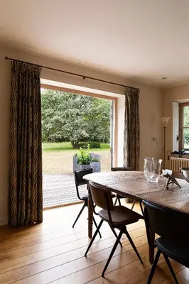 a dining room with a table and a large window at Bosvilla Kennemerduinen in IJmuiden