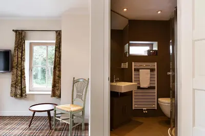 a bathroom with a sink and a toilet and a chair at Bosvilla Kennemerduinen in IJmuiden