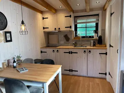a kitchen with white cabinets and a wooden table at Luxury Chalets Monnickendam in Monnickendam