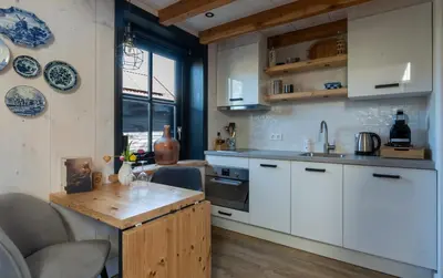 a kitchen with white cabinets and a wooden table at Luxury Chalets Monnickendam in Monnickendam