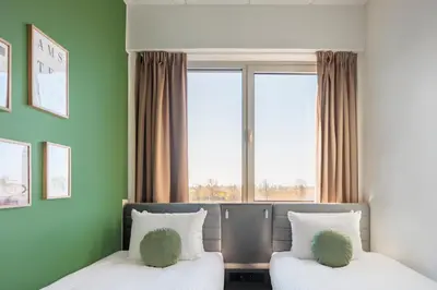 two beds in a room with green walls and a window at Maxhotel Amsterdam Airport Schiphol - Recently Renovated in Hoofddorp