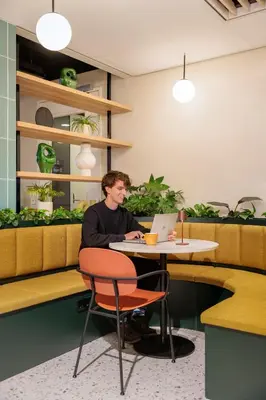 a man sitting at a table with a laptop at Maxhotel Amsterdam Airport Schiphol - Recently Renovated in Hoofddorp