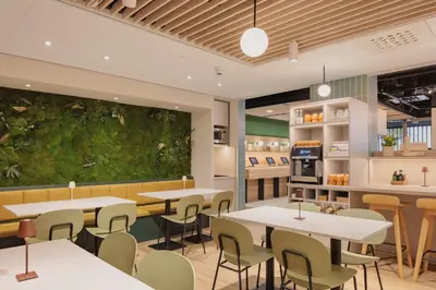 a restaurant with tables and chairs and a green wall at Maxhotel Amsterdam Airport Schiphol - Recently Renovated in Hoofddorp