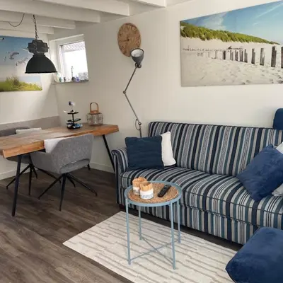 a living room with a couch and a desk at ZeeBedStay in Noordwijk aan Zee