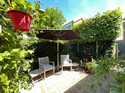 a patio with two chairs and an umbrella at ZeeBedStay in Noordwijk aan Zee