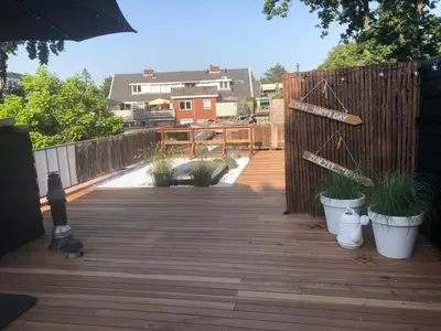 a wooden deck with potted plants and a fence at Bergenshofje in Bergen
