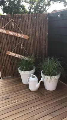 two potted plants sitting on a deck with a happy day sign at Bergenshofje in Bergen