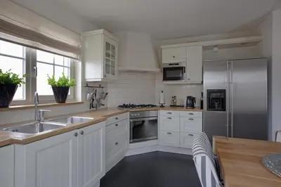 a kitchen with white cabinets and a stainless steel refrigerator at Holiday Home Zeewolde in Zeewolde