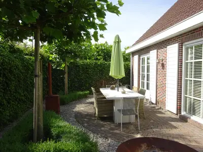 a patio with a table and a green umbrella at Holiday Home Zeewolde in Zeewolde