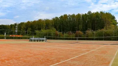 a tennis court with a bench on the court at Holiday Home Zeewolde in Zeewolde