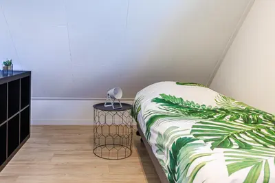 a bedroom with a bed and a nightstand with a green bedspread at Holiday Home Zeewolde in Zeewolde