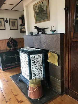 a living room with a fireplace with a cat on the mantle at De Sloep in Bergen