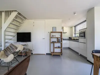 a living room with a staircase and a kitchen at Beautiful Holiday home near the sea in Egmond aan den Hoef