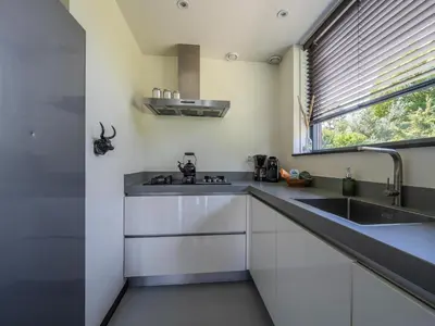 a kitchen with white cabinets and a sink and a window at Beautiful Holiday home near the sea in Egmond aan den Hoef