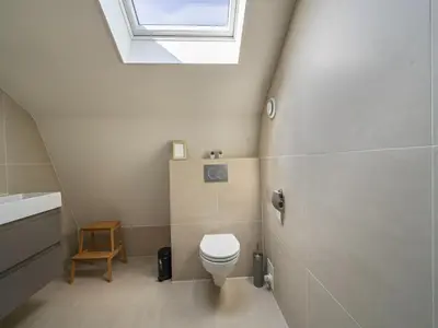 a bathroom with a toilet and a skylight at Beautiful Holiday home near the sea in Egmond aan den Hoef