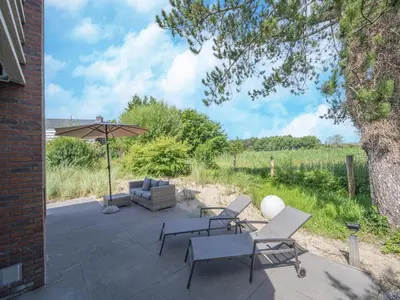 a patio with a table and chairs and an umbrella at Beautiful Holiday home near the sea in Egmond aan den Hoef