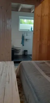 a bedroom with a bed and a bathroom with a toilet at Tuinhuis in Lutjewinkel