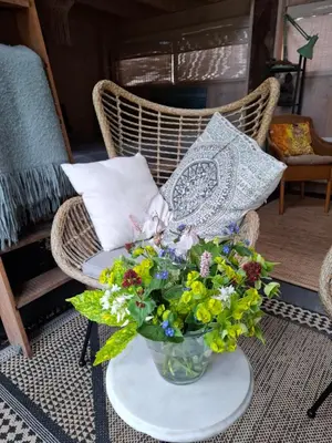 a wicker chair with a vase of flowers on a table at Tuinhuis in Lutjewinkel