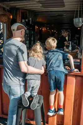 a man and two children standing at a bar at Basecamp Tiny House Eco-resort IJmuiden in IJmuiden