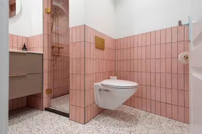 a bathroom with a toilet and pink tile walls at KUST Zandvoort Private Parking included in Zandvoort