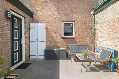 a patio with chairs and a door and a building at KUST Zandvoort Private Parking included in Zandvoort