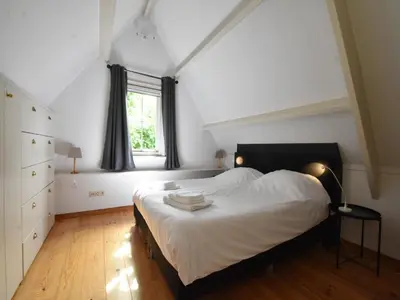 a bedroom with a bed with white sheets and a window at Serene Getaway in Edam in Edam