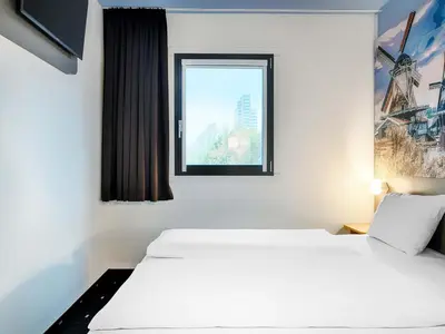 a hotel room with two beds and a window at B&B Hotel Amsterdam-Zaandam in Zaandam