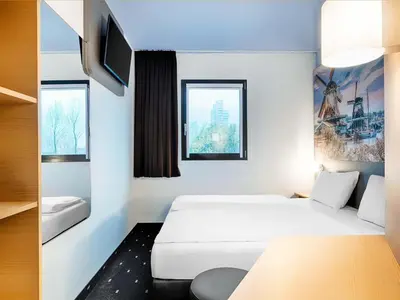 a hotel room with two beds and a tv at B&B Hotel Amsterdam-Zaandam in Zaandam