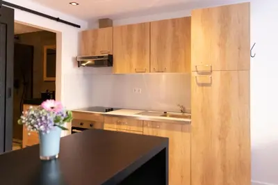 a kitchen with wooden cabinets and a table with a vase of flowers at Studio 23 in Zandvoort