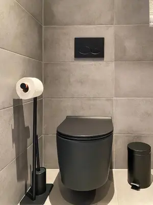 a bathroom with a black toilet and a roll of toilet paper at Studio 23 in Zandvoort
