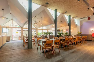 a dining room with tables and chairs and windows at Hans Brinker Hostel Amsterdam in Amsterdam