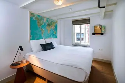 a bedroom with a large white bed and a window at Hello I'm Local - Boutique Hostel in Haarlem