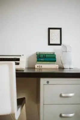a desk with a pile of books and a picture at Hello I'm Local - Boutique Hostel in Haarlem