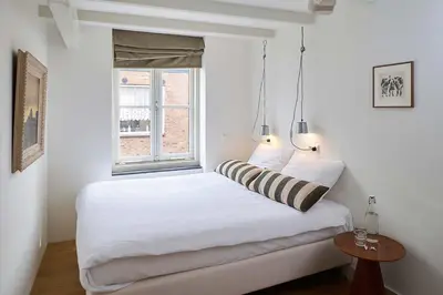 a white bedroom with a bed and a window at Hello I'm Local - Boutique Hostel in Haarlem
