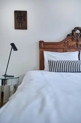 a bed with a wooden headboard and a table with a lamp at Hello I'm Local - Boutique Hostel in Haarlem