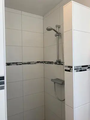 a shower in a bathroom with white tiles at B&B Diemerplein in Amsterdam