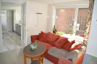 a living room with a red couch and a table at Bijzonder Bakkum in Castricum