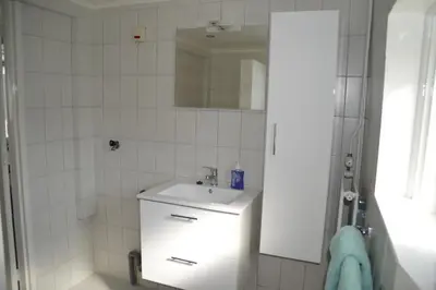 a white bathroom with a sink and a mirror at Bijzonder Bakkum in Castricum