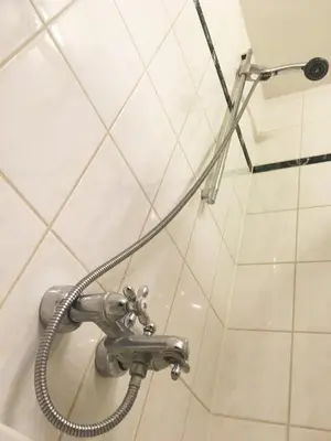 a shower faucet in a bathroom with white tiles at B&B Looier in Amsterdam