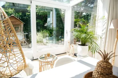 a screened in porch with plants and chairs at Luxury villa on peaceful location. Boat optional in Vinkeveen