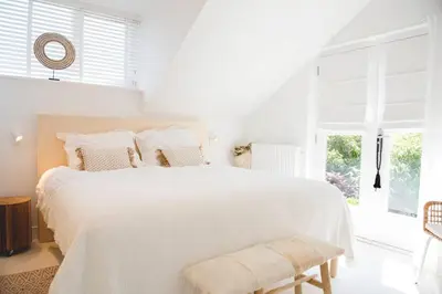 a white bedroom with a white bed and a window at Luxury villa on peaceful location. Boat optional in Vinkeveen