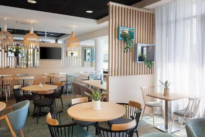 a restaurant with wooden tables and chairs at Hampton by Hilton Amsterdam Airport Schiphol in Hoofddorp