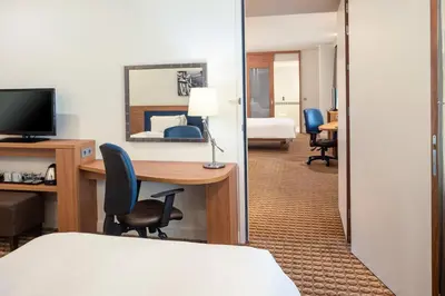 a hotel room with a desk and a bedroom at Hampton by Hilton Amsterdam Airport Schiphol in Hoofddorp