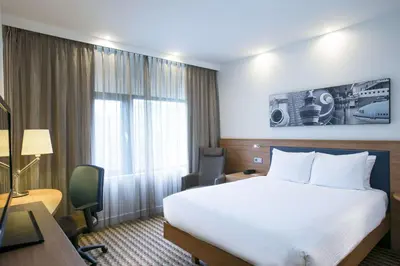 a hotel room with a white bed and a desk at Hampton by Hilton Amsterdam Airport Schiphol in Hoofddorp