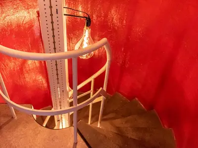 a metal staircase with a light on a red wall at SWEETS - Kortjewantsbrug in Amsterdam